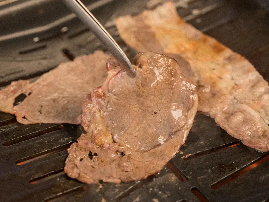 Guests grilling meat together at their table, capturing the laid-back social dining style at Raku Raku